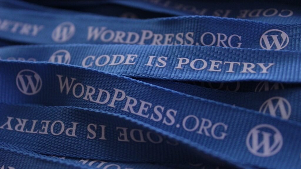 lue lanyards printed with the WordPress.org logo and the slogan “Code is Poetry,” representing WordPress website development and coding culture.