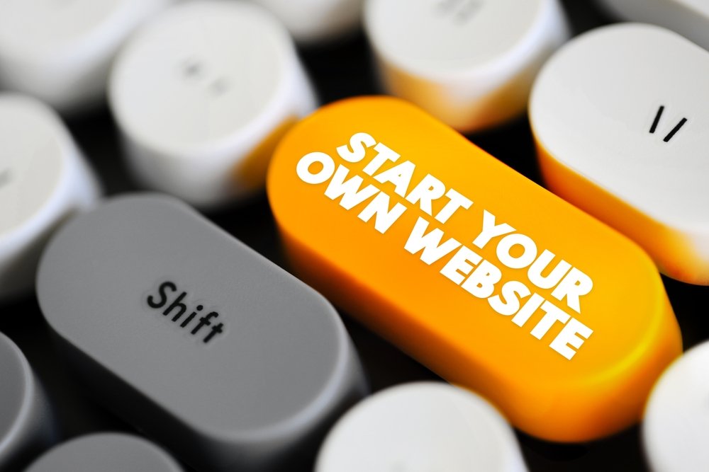 Close-up of a computer keyboard with a bright yellow key labeled “Start Your Own Website” next to a gray Shift key, symbolizing launching a business website.